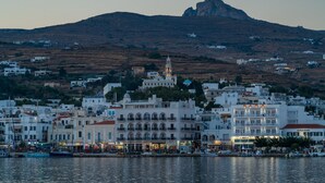 Un pueblo costero con edificios blancos, una iglesia destacada con campanario y una colina al fondo.