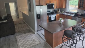 Una cucina moderna con mobili in legno, elettrodomestici in acciaio inossidabile e un'isola centrale con sgabelli da bar.