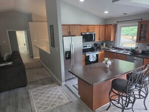 A modern kitchen with wooden cabinets, stainless steel appliances, and a central island with bar stools.