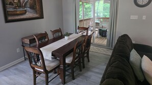 Zona pranzo con tavolo e sedie in legno, un lampadario e un dipinto raffigurante una fontana.
