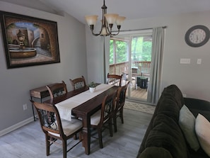 A dining area with a wooden table and chairs, a chandelier, and a painting of a fountain.