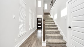Un intérieur moderne avec un escalier recouvert de moquette, des murs blancs et un plancher en bois.