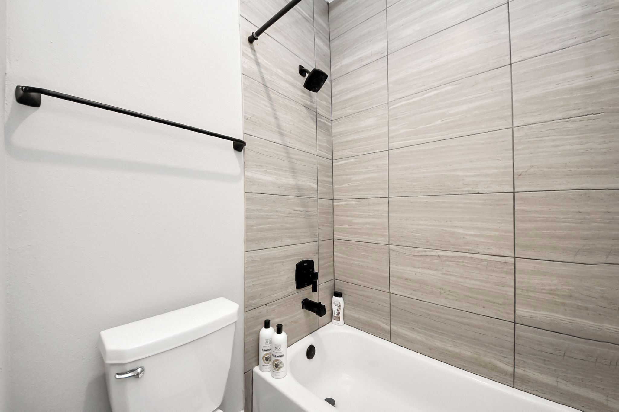 Een moderne badkamer met toilet, bad en douchehoek.