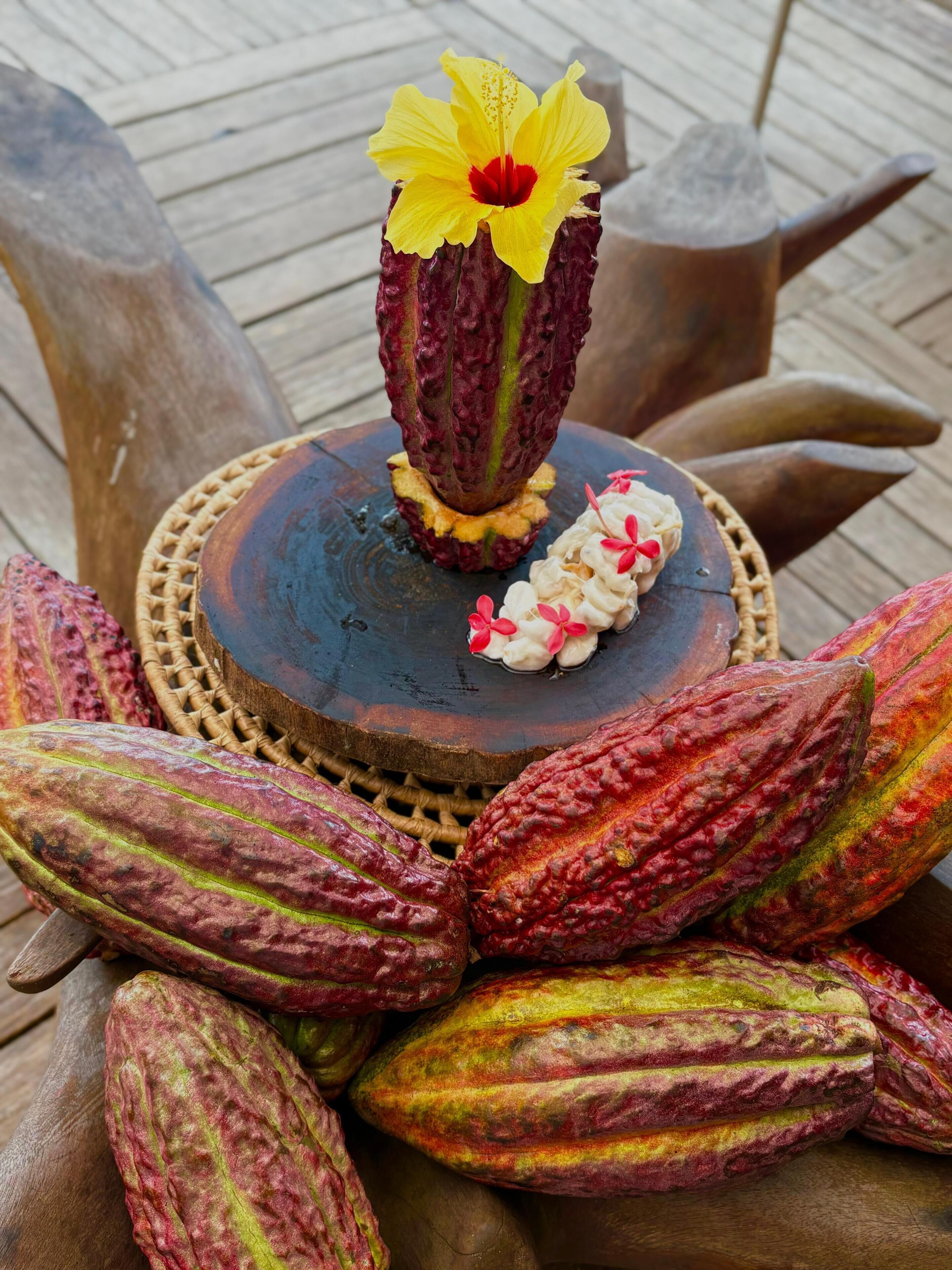 Una mesa con un arreglo floral y vainas de cacao.