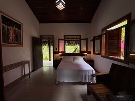 Un dormitorio con cama, mesitas de noche, un banco y un cuadro en la pared.