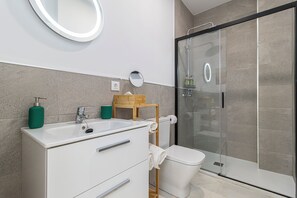 A modern bathroom with a shower, toilet, and sink.