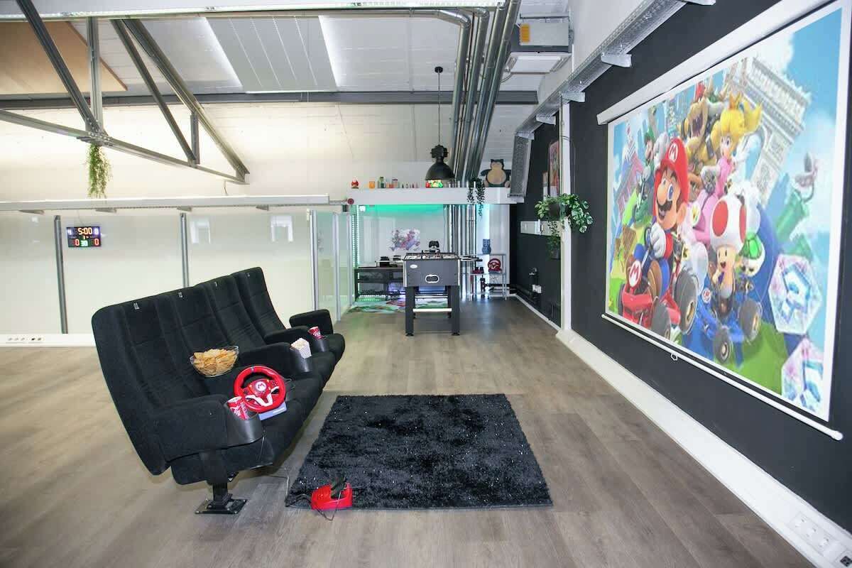 A modern living room with a black sofa, a black rug, and a large Mario-themed poster on the wall.