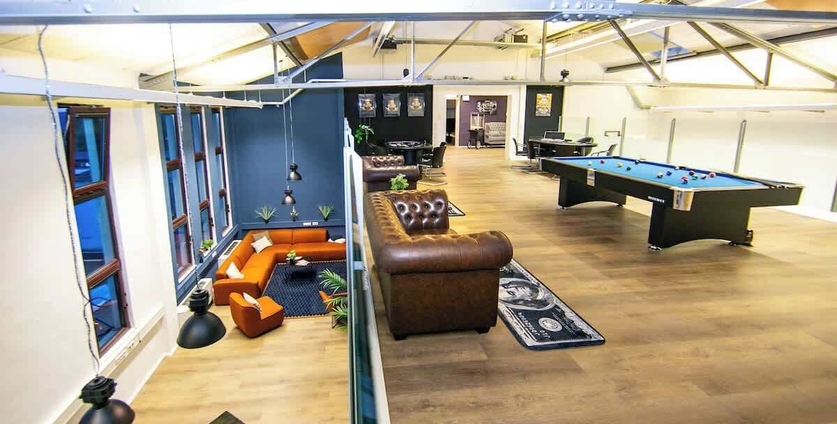Un amplio espacio interior con mesa de billar, cómodos sofás de cuero y mesa de futbolín.