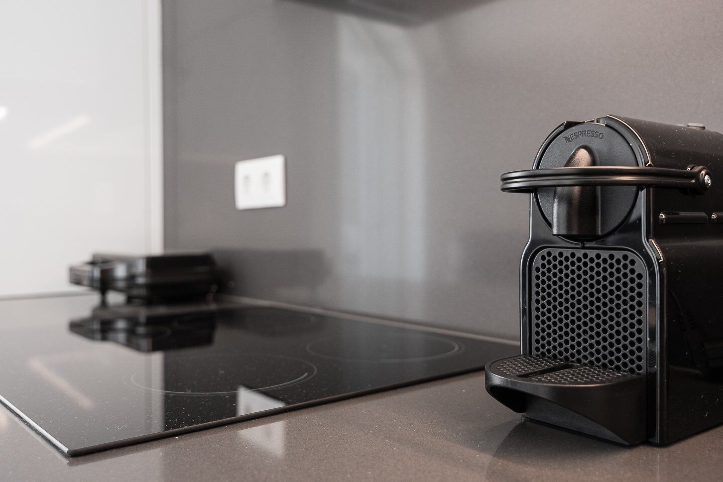 A modern kitchen with a black coffee machine on a sleek countertop.