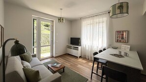 A modern living room with a sofa, coffee table, TV, and dining area with chairs and a table.