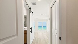 A hallway with a view of the ocean through large windows. - 30A Beachfront | Pool  | Spooky Palms  | Sleeps 10 | Gulf View (Santa Rosa Beach)