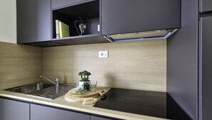 A modern kitchen with a stainless steel sink, a cutting board with a plant, and a glass. - Modern Flat With Terrace in Bibione (San Michele al Tagliamento)