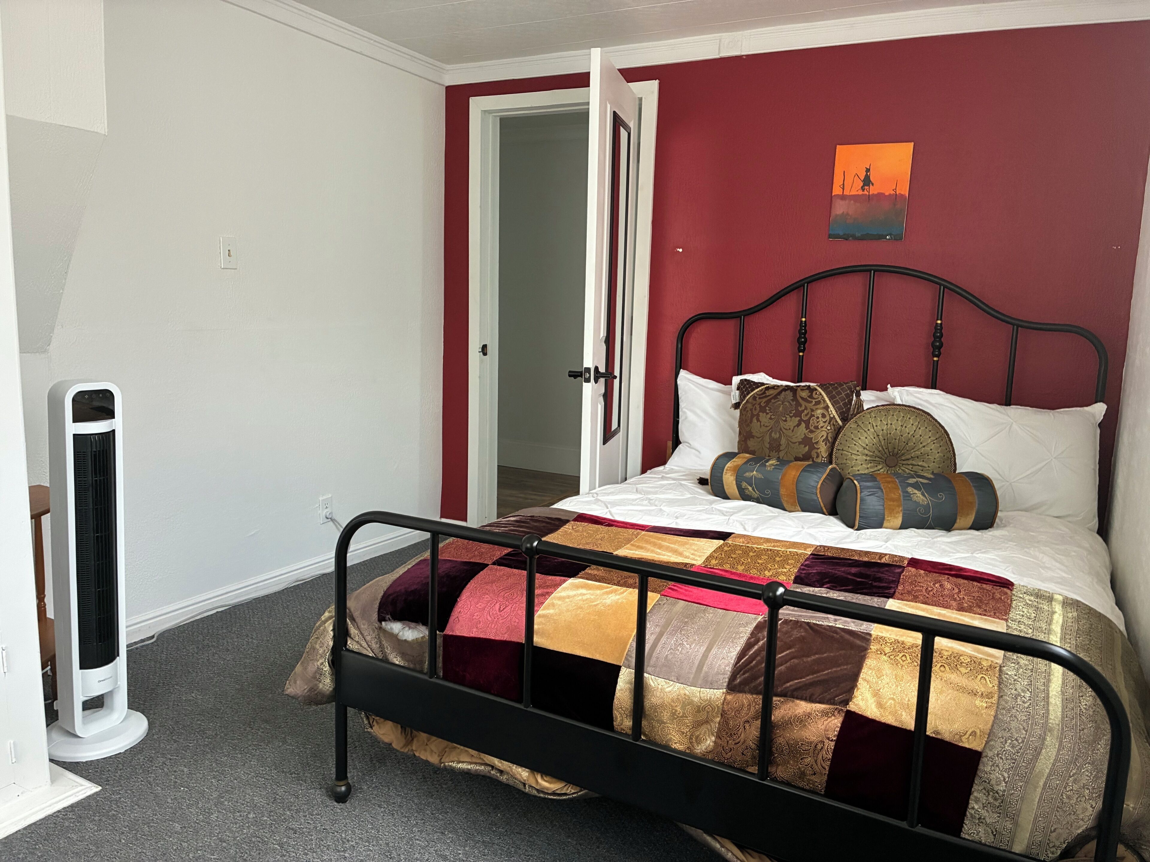 Una camera da letto con un letto, un termosifone e una porta che dà su un'altra stanza.