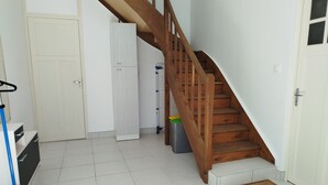 A clean, well-lit hallway with a wooden staircase, a white door, and a blue cart.