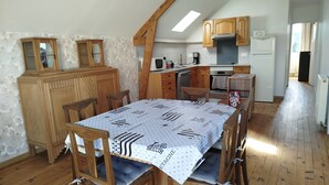 A cozy kitchen with wooden cabinets, a dining table with chairs, and a built-in oven.