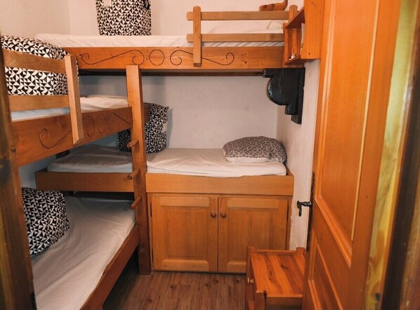 A bunk bed room with a wooden cabinet and a small table.