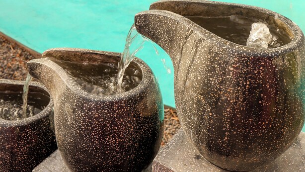 A poolside area with lounge chairs and stone water features.