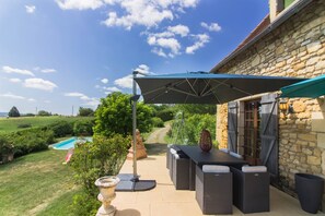 A patio area with a stone wall, outdoor furniture, and a pool.