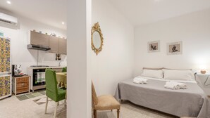 Un dormitorio con cama, una silla, un escritorio y una kitchenette.
