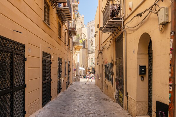 Una calle estrecha flanqueada por edificios con balcones, rejas de hierro forjado y un cielo despejado.