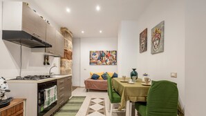 Cocina compacta con estufa, horno y comedor con mesa y sillas.