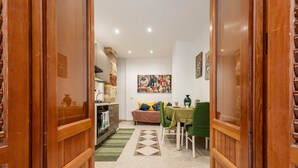 Un vano de puerta de madera que da a un comedor con una mesa, sillas y un sofá.