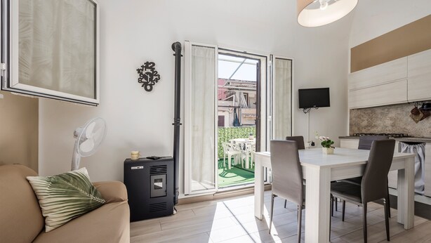 Een moderne woonkamer met een bank, een eettafel en een keukenhoek met kasten en een televisie.