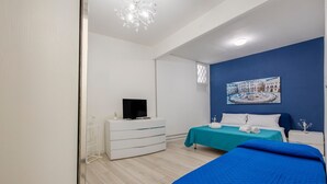 Een slaapkamer met een bed, een televisie op een dressoir, een schilderij aan de muur en een raam.