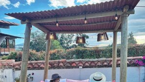 A wooden pergola with a blue patterned tablecloth, two people seated on a bench, and a bottle of wine on the table. - hotel san mateo  (Nobsa)