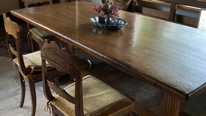 Comedor con una gran mesa de madera, seis sillas y un jarrón con flores.
