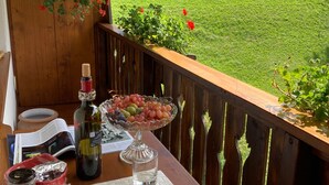 Una terraza de madera con una mesa dispuesta para una comida, con vistas a un campo verde y montañas.