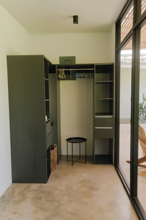A compact room with a built-in wardrobe, a small table, and a bench.