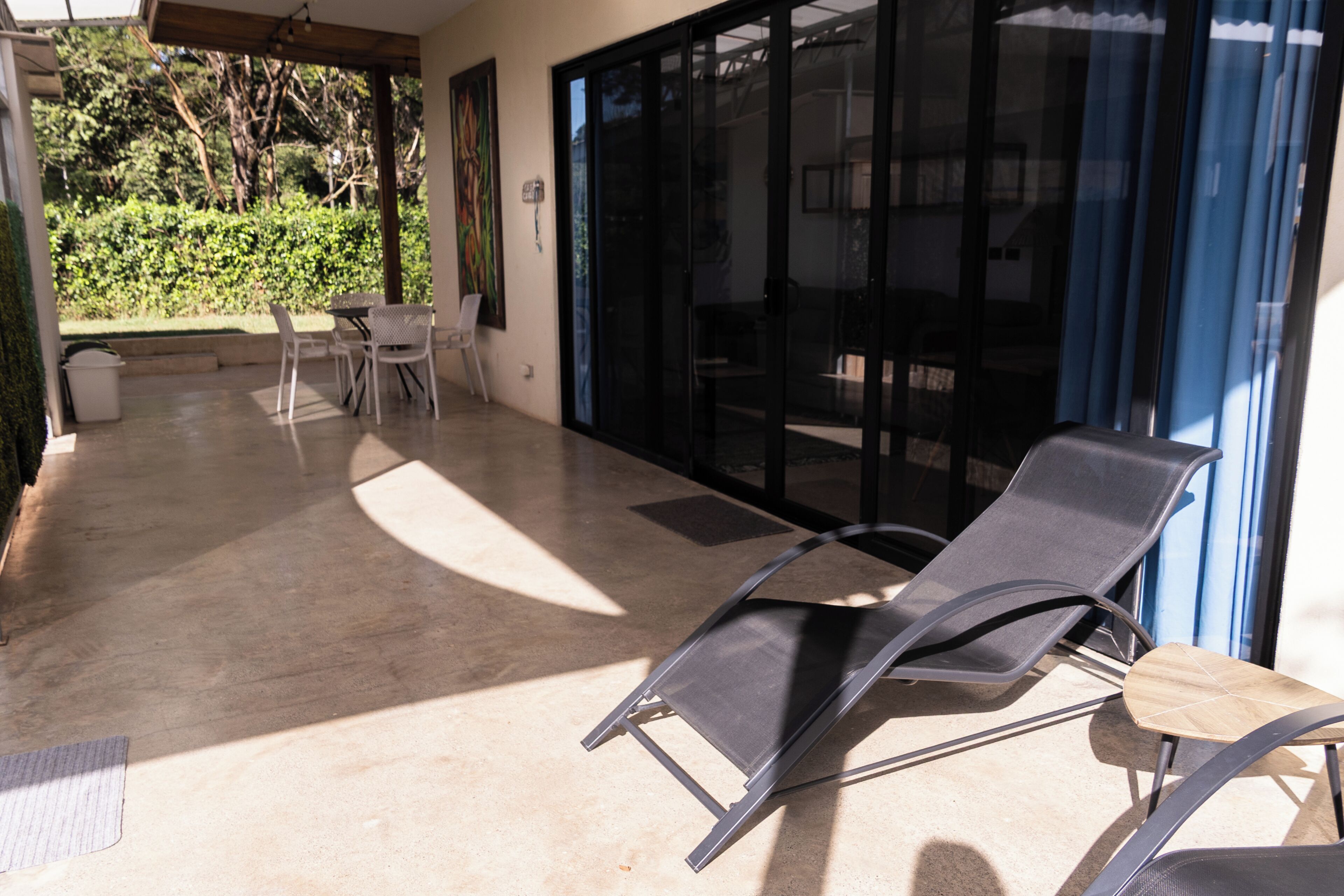 A sunlit patio with a lounge chair, a table, and chairs.