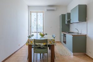 Une cuisine compacte avec un coin repas, une fenêtre avec des rideaux et un petit évier.