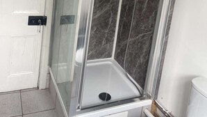 Une douche entièrementClose avec des parois en verre, un mur en marbre, une porte blanche et un sol carrelé.