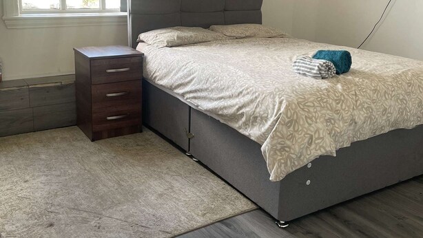 Une chambre à coucher avec un lit, une table de chevet, une télévision et une fenêtre.