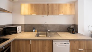 A modern kitchen with wooden cabinets, a built-in microwave, a sink, and a dishwasher. - Vacation Apartment by Lake Annecy in Sevrier (Sevrier)
