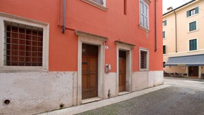 A building with a red facade, a cobblestone street, and a visible door with a number 7 sign. - GuestHost - Cozy 50 sqm studio apartment, perfect for a stay of two people, located on the first floor of a building with elevator (NOT suitable for disabled people).The property is located in the San Zeno district, a few steps from the Museum and the ma (Verona)