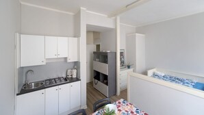A compact kitchen with white cabinets, a gas stove, and a sink. There is a dining area with a table and chairs. - GuestHost - Cozy 50 sqm studio apartment, perfect for a stay of two people, located on the first floor of a building with elevator (NOT suitable for disabled people).The property is located in the San Zeno district, a few steps from the Museum and the ma (Verona)