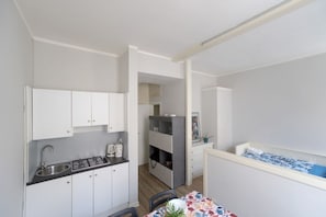 A compact kitchen with white cabinets, a gas stove, and a sink. There is a dining area with a table and chairs.