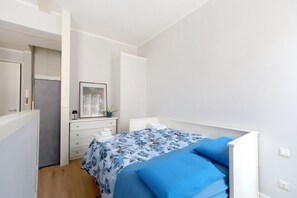 Ein Schlafzimmer mit Bett, Schminktisch, Spiegel und Heizkörper.