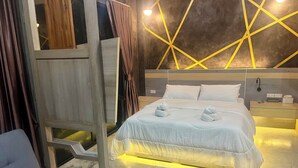 A modern hotel room with a large bed, bedside tables, and a unique geometric wall design. - Darisa home  ที่พักใกล้ตัวเมืองสุราษฎร์ธานี เพียง 6 กิโลเมตร บรรยากาศดีมาก (เมือง)
