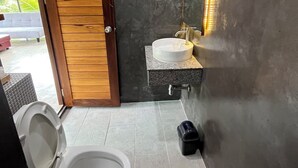 A modern bathroom with a wooden door, a white toilet, a sink with a granite countertop, and a mirror with LED lights. - Darisa home  ที่พักใกล้ตัวเมืองสุราษฎร์ธานี เพียง 6 กิโลเมตร บรรยากาศดีมาก (เมือง)