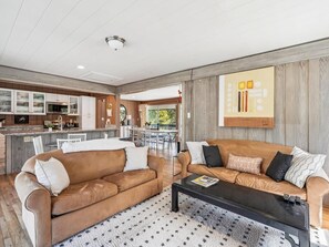 Una sala de estar moderna con un conjunto de sofá, una mesa de centro y una cocina al fondo.