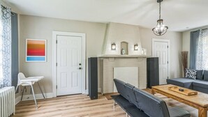 A modern living room with a fireplace, a dining table, a sofa, and a high chair. - 4BR Pitt Suburbs Gem (Pittsburgh)