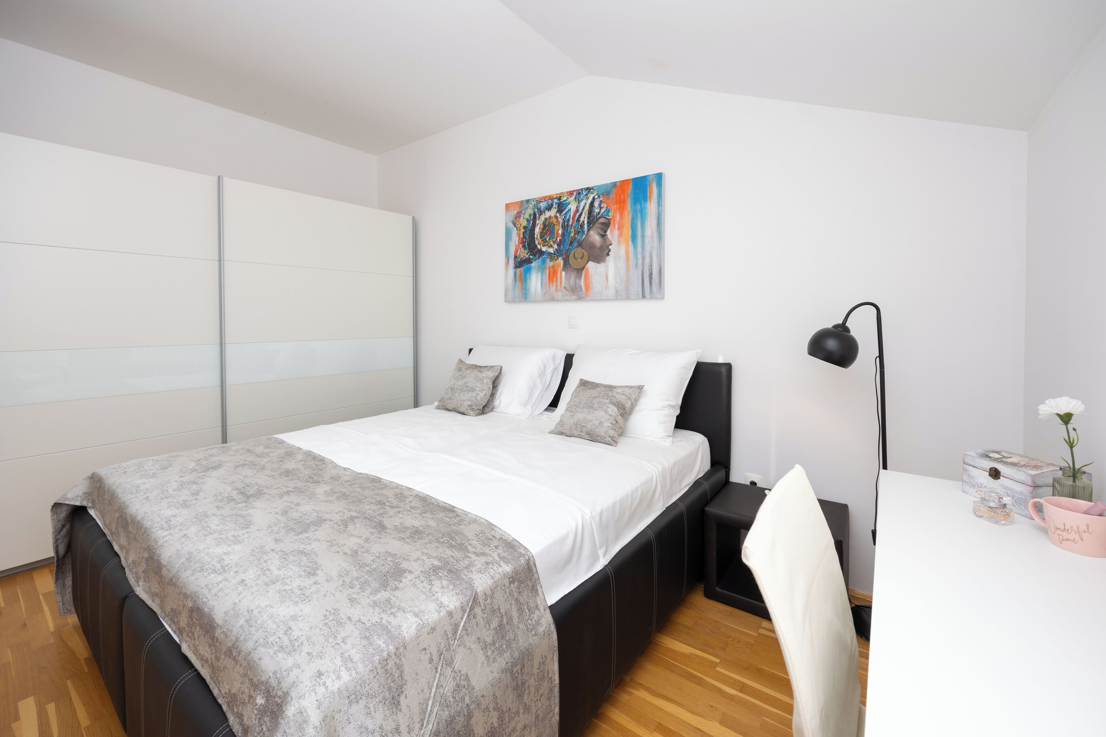 Une chambre à coucher moderne avec un lit, une table de chevet et un tableau accroché au mur.