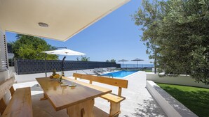 A wooden outdoor dining area with a pool in the background. - Breathtaking villa W Seaview & heated pool (Kučine)