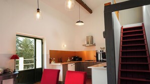 Una cocina moderna con comedor, una escalera y un ventanal con vistas a árboles.