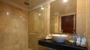 Une salle de bain moderne avec une douche à parois de verre, un lavabo blanc et un meuble-lavabo en bois.