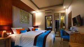 Une chambre d’hôtel avec un grand lit, un bureau et une chaise. Un miroir est accroché au mur et un téléviseur est fixé au-dessus du bureau.